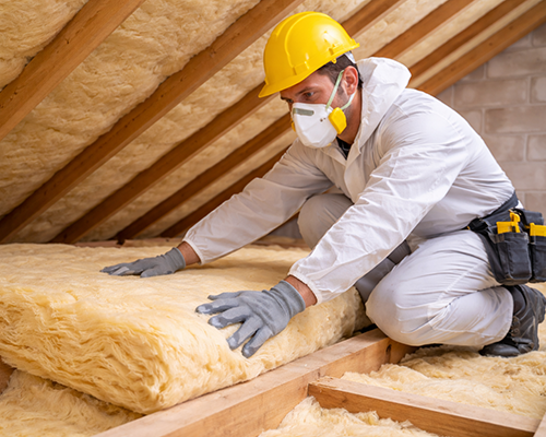 Artisan posant un isolant thermique dans des combles